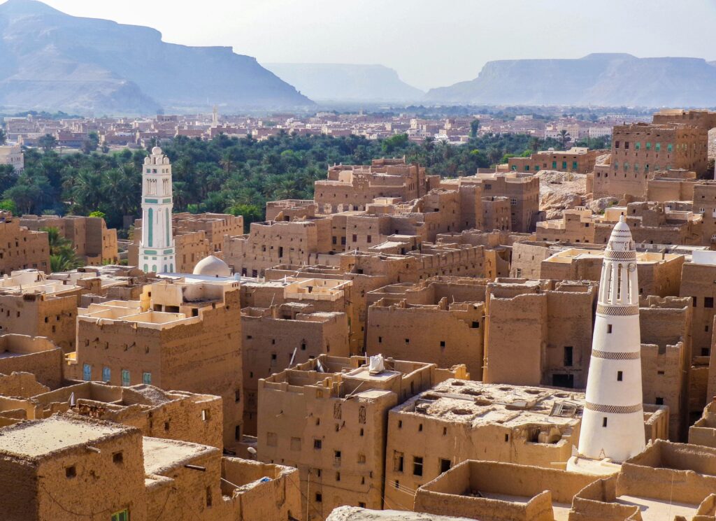 Aerial view showcasing the traditional architecture of a historic town in Yemen with iconic towers and desert landscape.